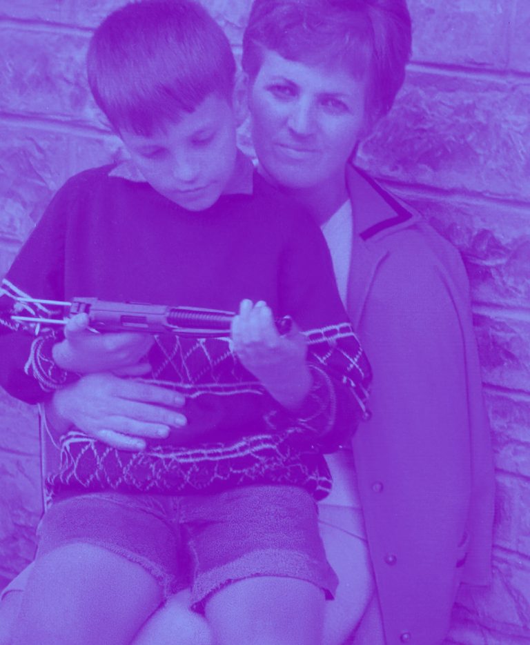 Una donna tiene in braccio un bambino in una fotografia di famiglia d'epoca, in duotone viola e azzurro