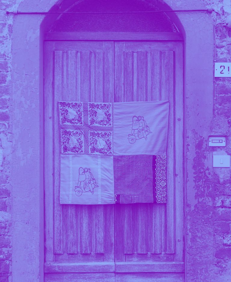 Un libro tessile ricamato appeso alla porta di legno di una casa, in duotone viola e azzurro