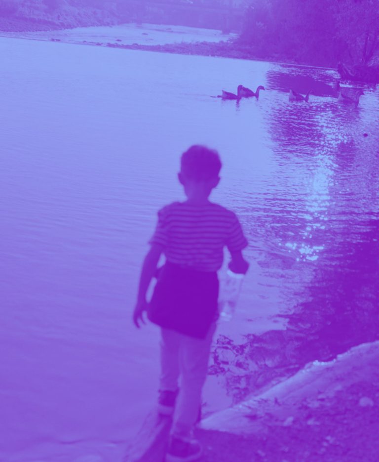 Un bambino di spalle sulla riva di un lago, in duotone viola e azzurro